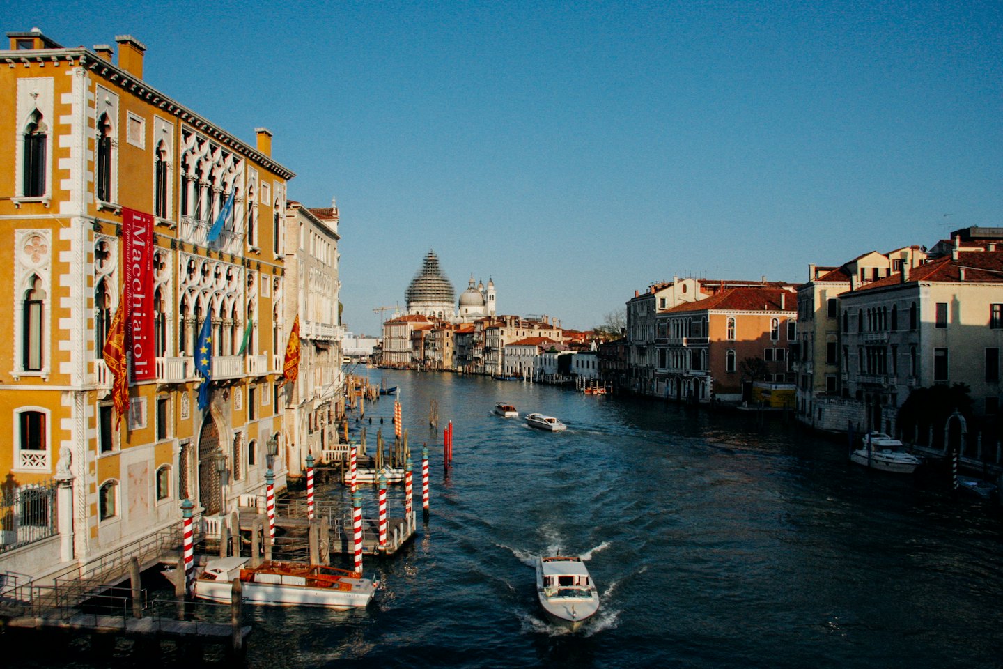 Barche navigano lungo un canale fiancheggiato da storici edifici veneziani.